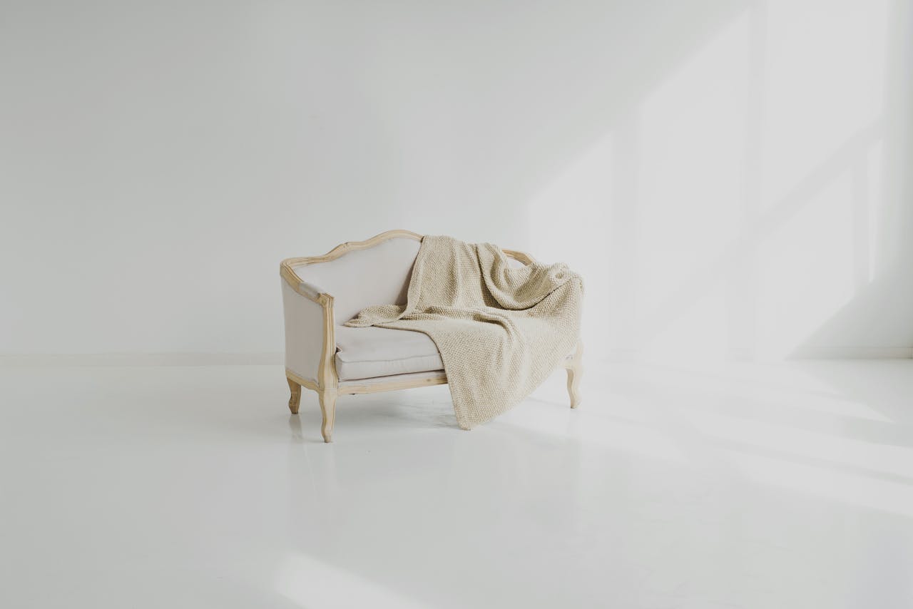 A beige throw on a vintage white sofa in a bright minimalist living space.